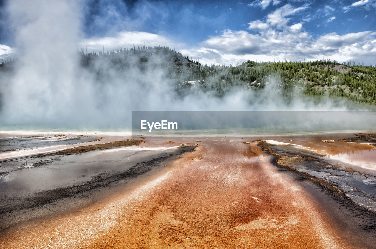 Scenic view of geyser and mountain against sky