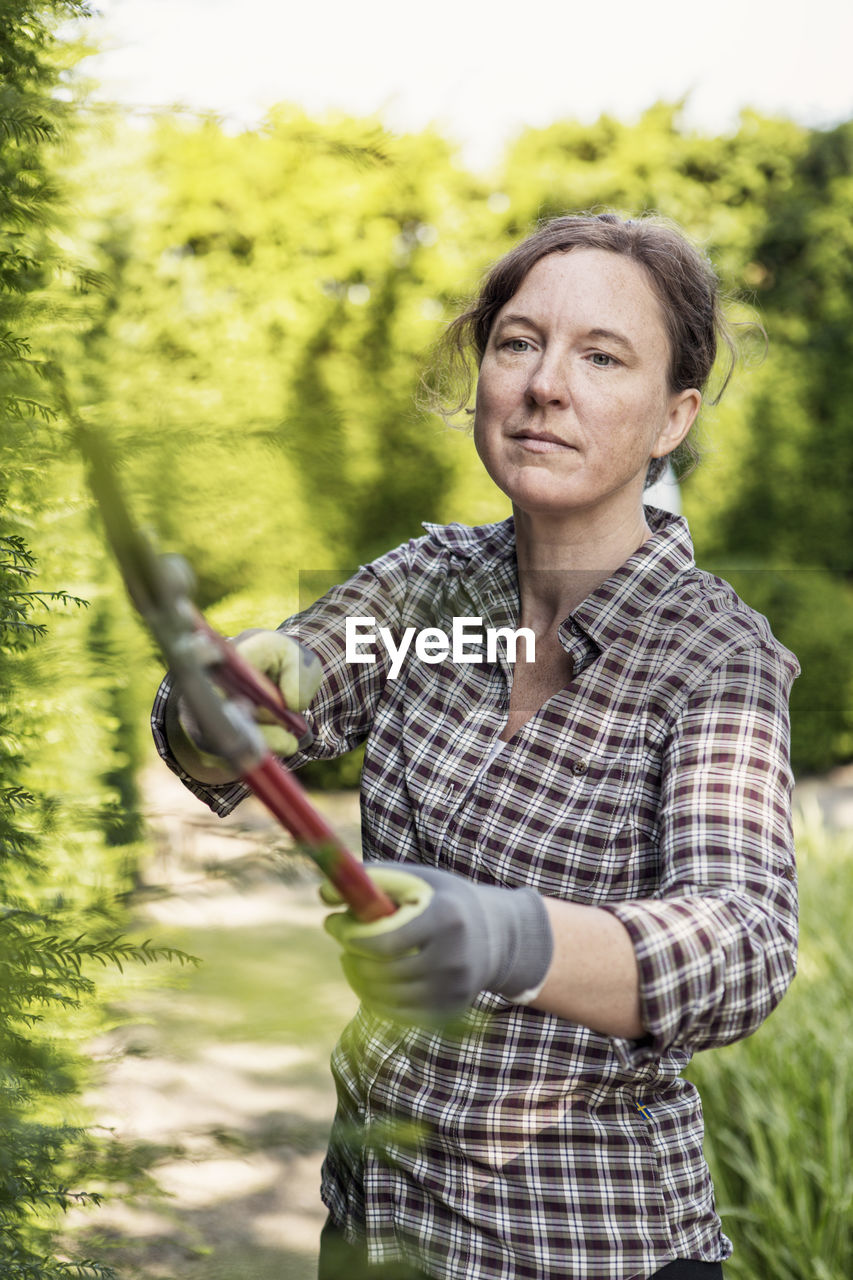 Mature woman cutting plants with pruning shears