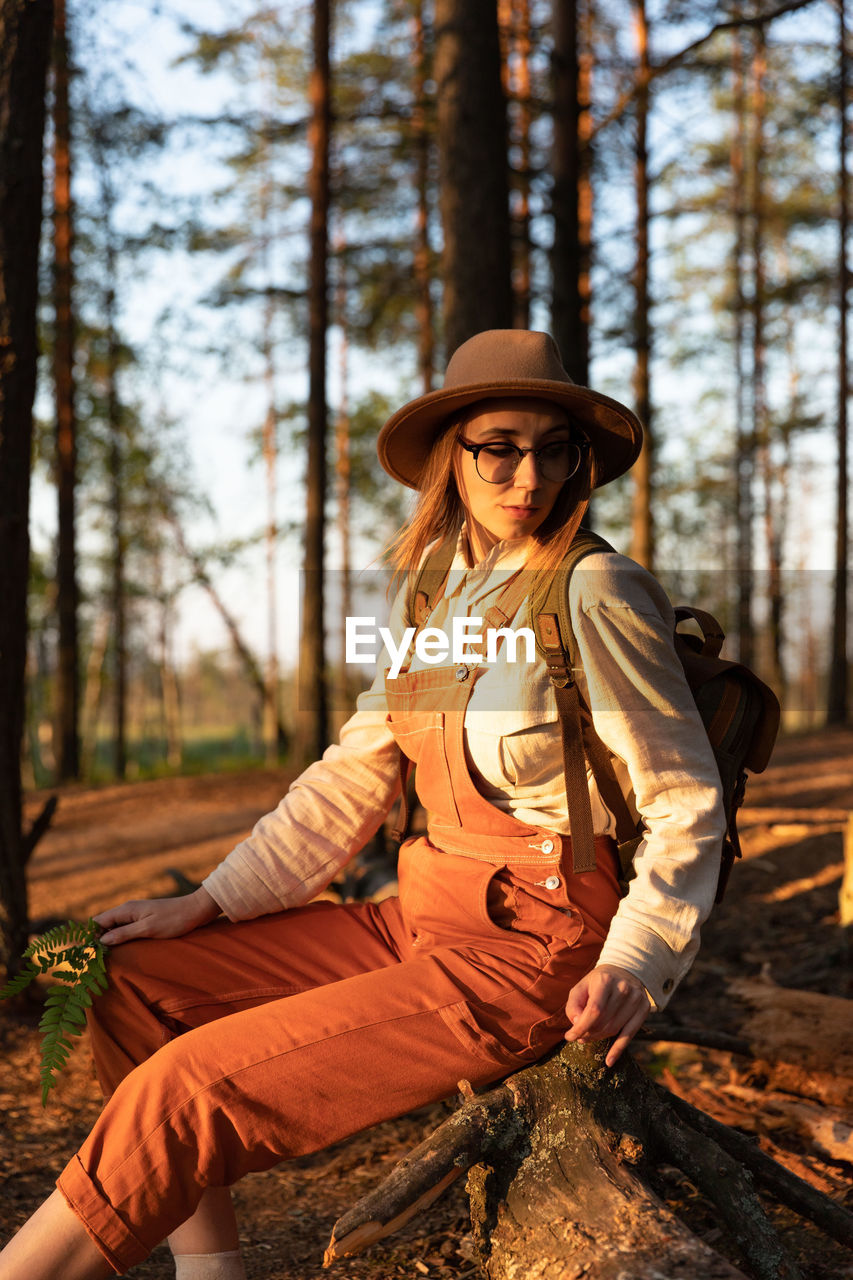 Woman botanist on ecological hiking trail in summer. naturalist exploring wildlife and ecotourism.