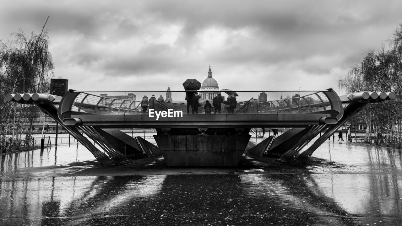 PEOPLE STANDING ON BOAT IN WATER AGAINST SKY