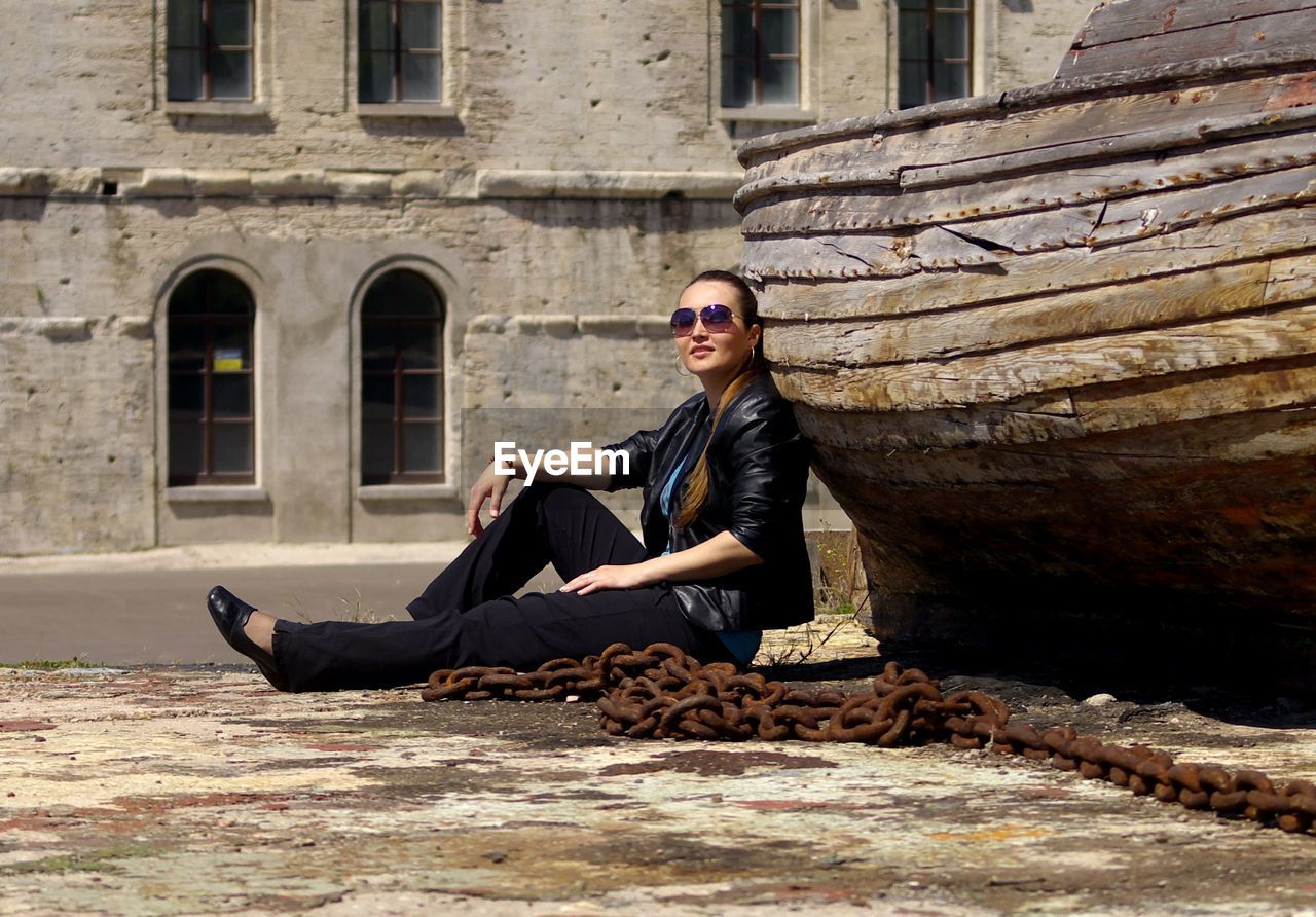 Portrait of woman sitting by rusty chain