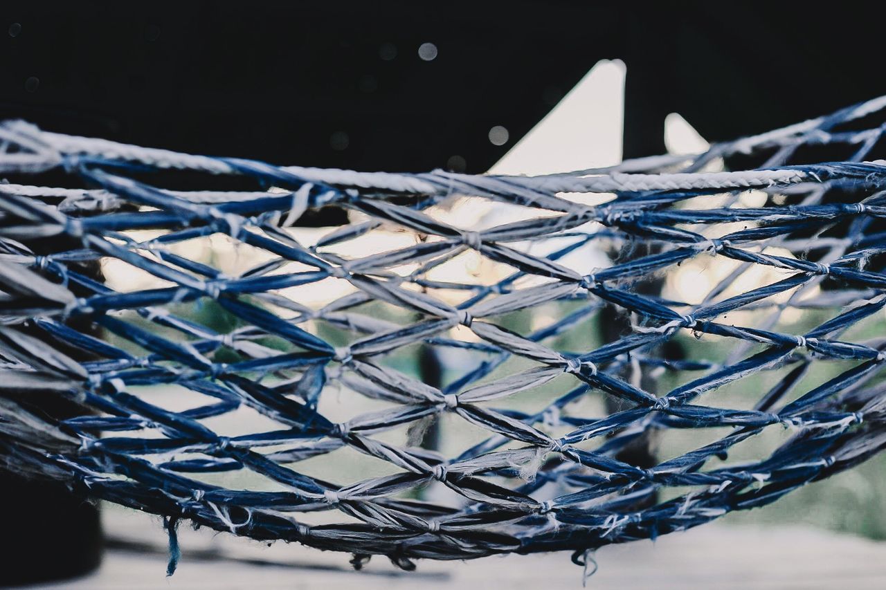 CLOSE-UP OF METAL FENCE AGAINST BLURRED BACKGROUND