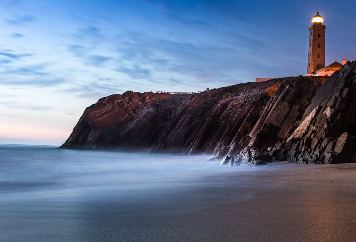 Illuminated lighthouse on cliff 