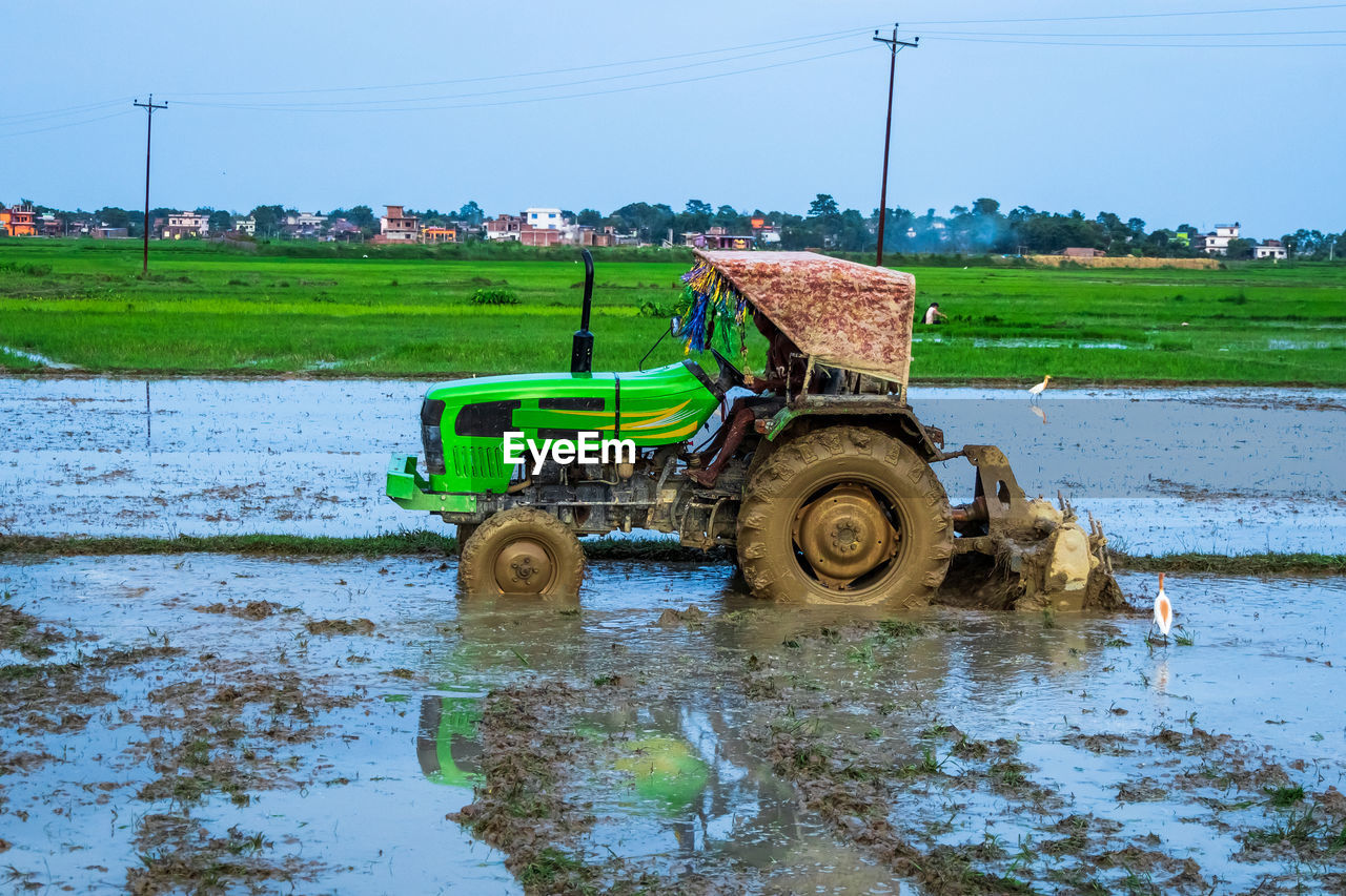 Tractor ploughs field. heavy duty tractor ploughs through muddy field after monsoon rain