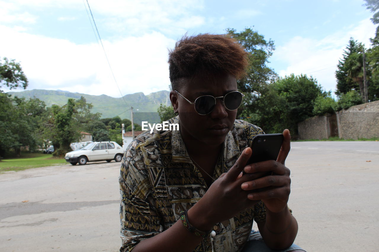 Woman using mobile phone while crouching on road