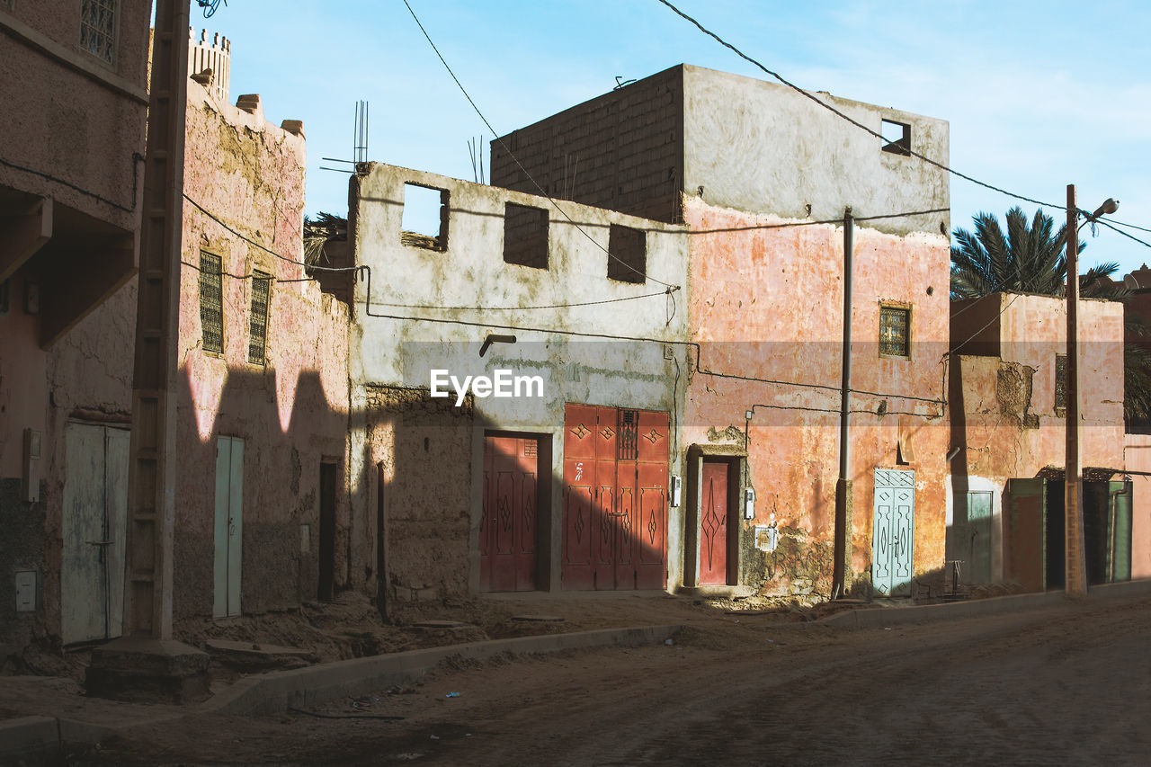 Ghost town in sahara desert with decadent abandoned house and dirt sand road, morocco