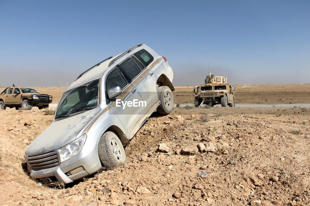 car, mode of transportation, transportation, off-roading, motor vehicle, vehicle, land vehicle, land, sky, nature, landscape, environment, desert, natural environment, off-road vehicle, clear sky, 4x4, dirt, copy space, blue, no people, day, sunny, climate, travel, arid climate, wheel, outdoors, sports utility vehicle, sunlight, scenics - nature