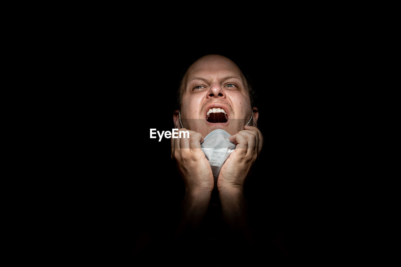 Portrait of a man with mask looking away from camera against black background