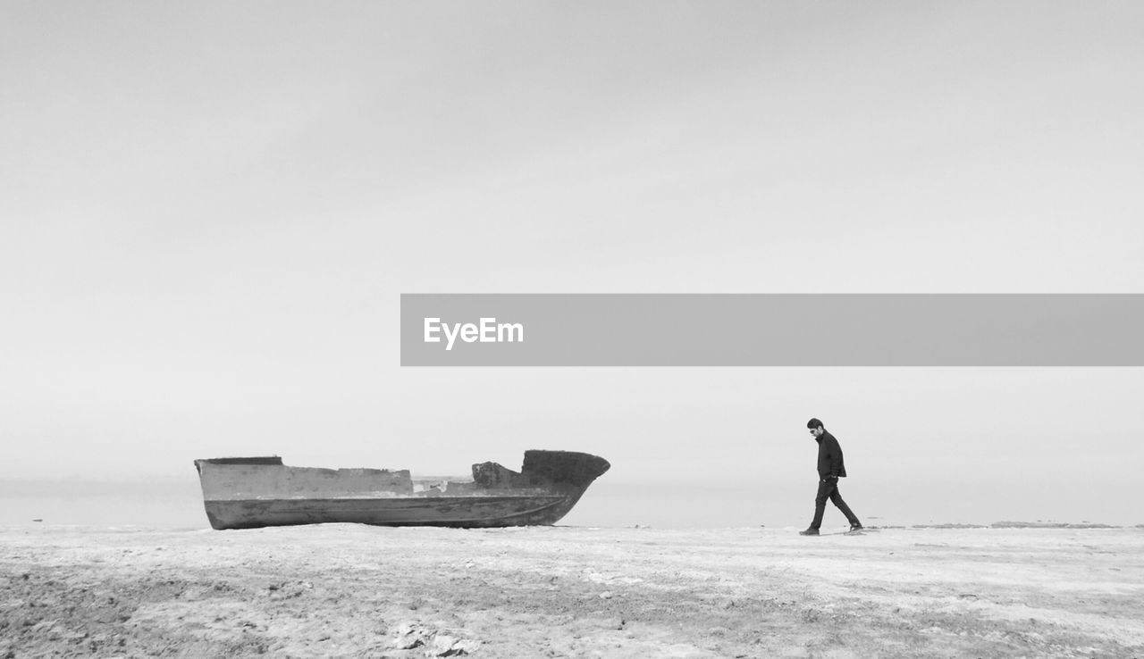 MAN ON BEACH BY SEA AGAINST SKY