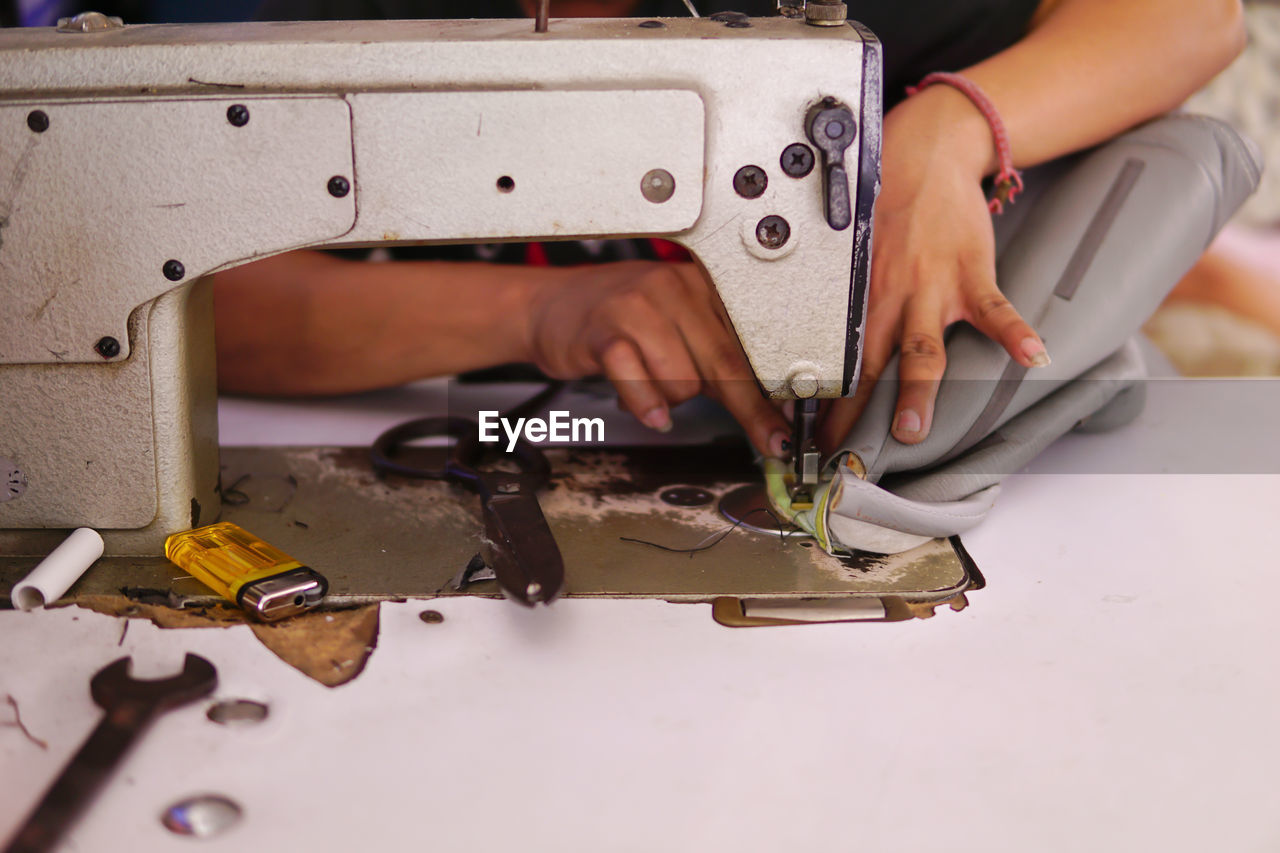Midsection of woman using sewing machine on table