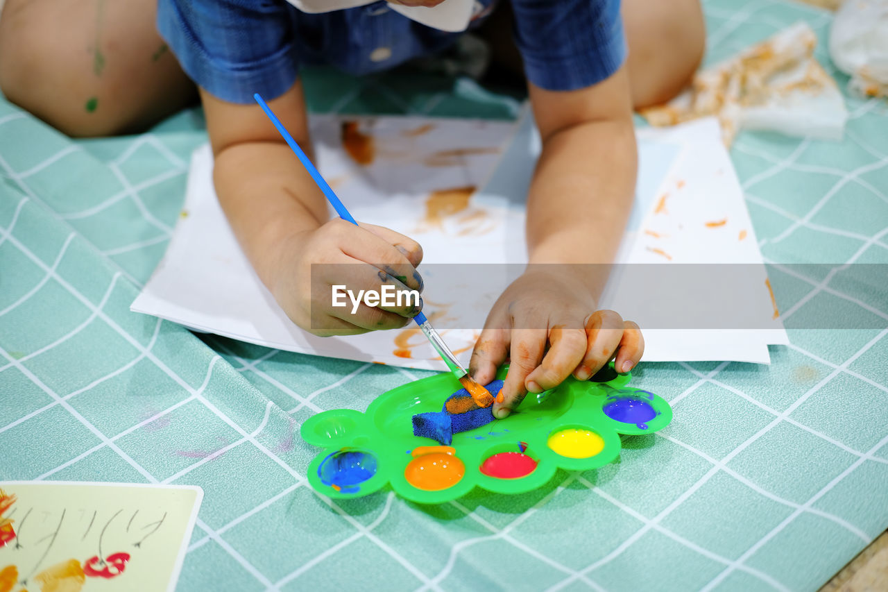 LOW SECTION OF BOY PLAYING WITH BALL ON TABLE