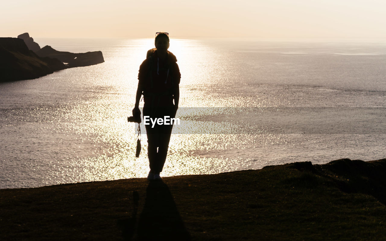 REAR VIEW OF SILHOUETTE MAN STANDING ON BEACH