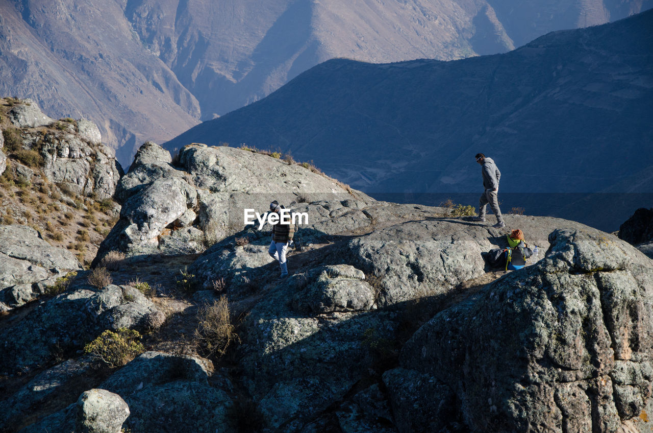 People on rocks against mountains