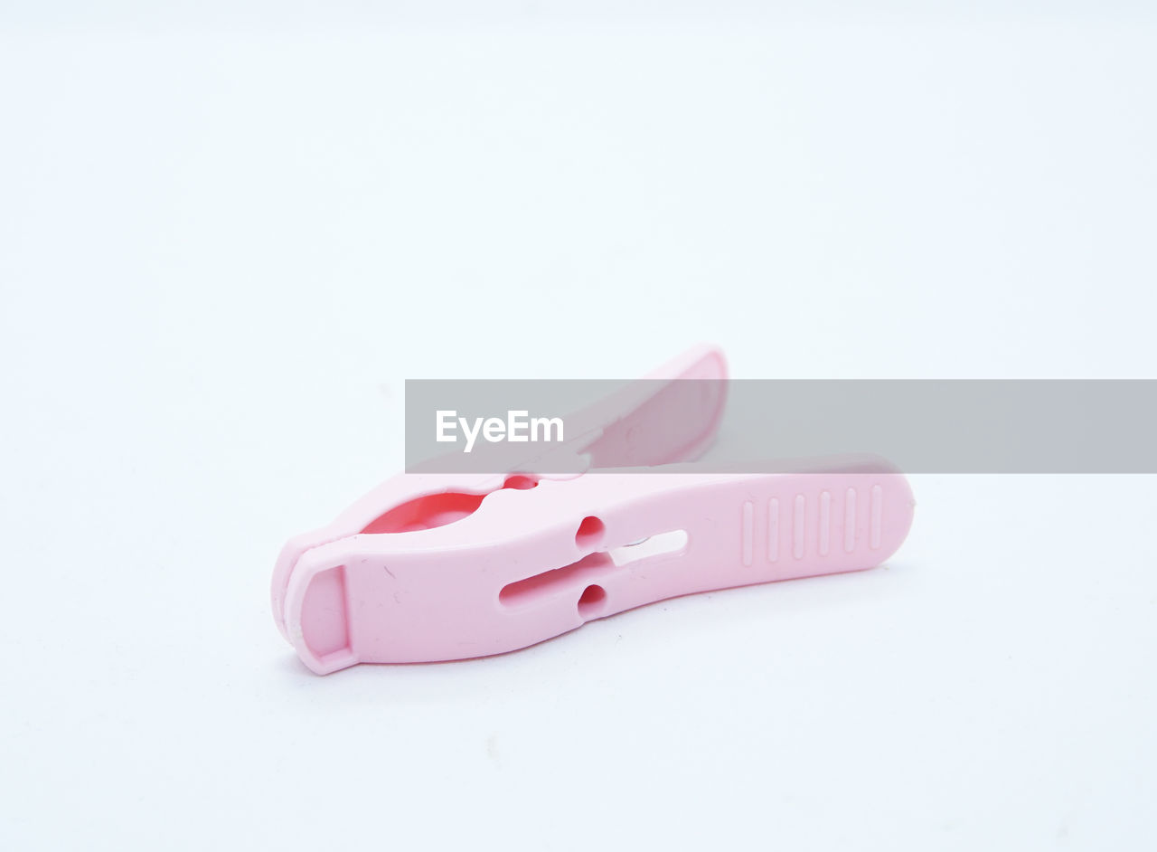 Close-up of pink clothespin over white background