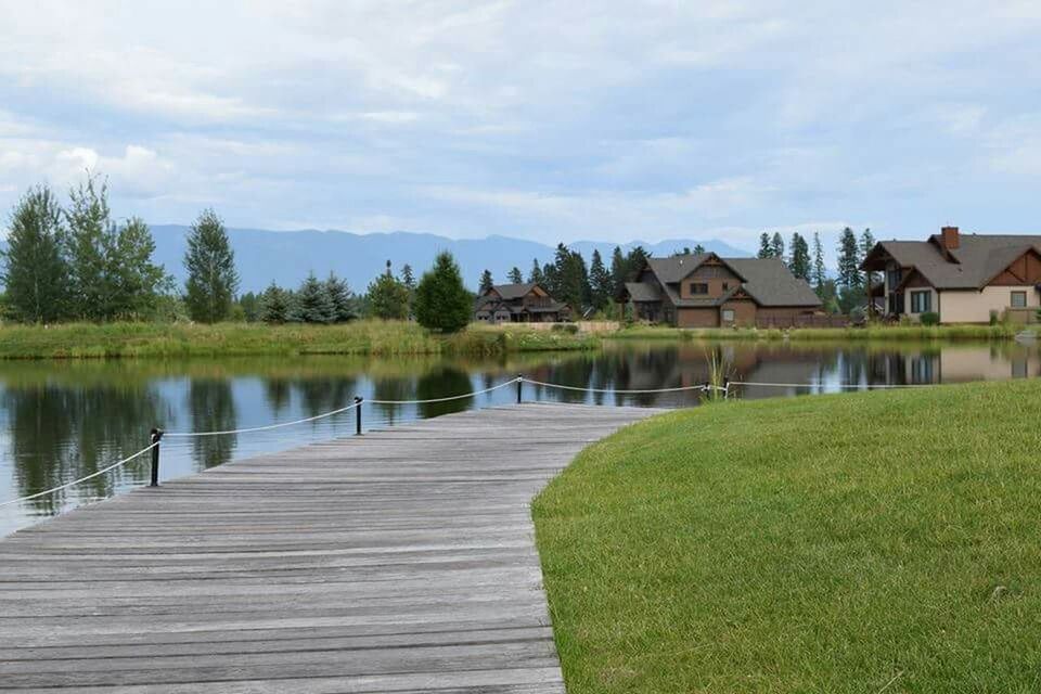 CALM LAKE WITH TREES IN FOREGROUND