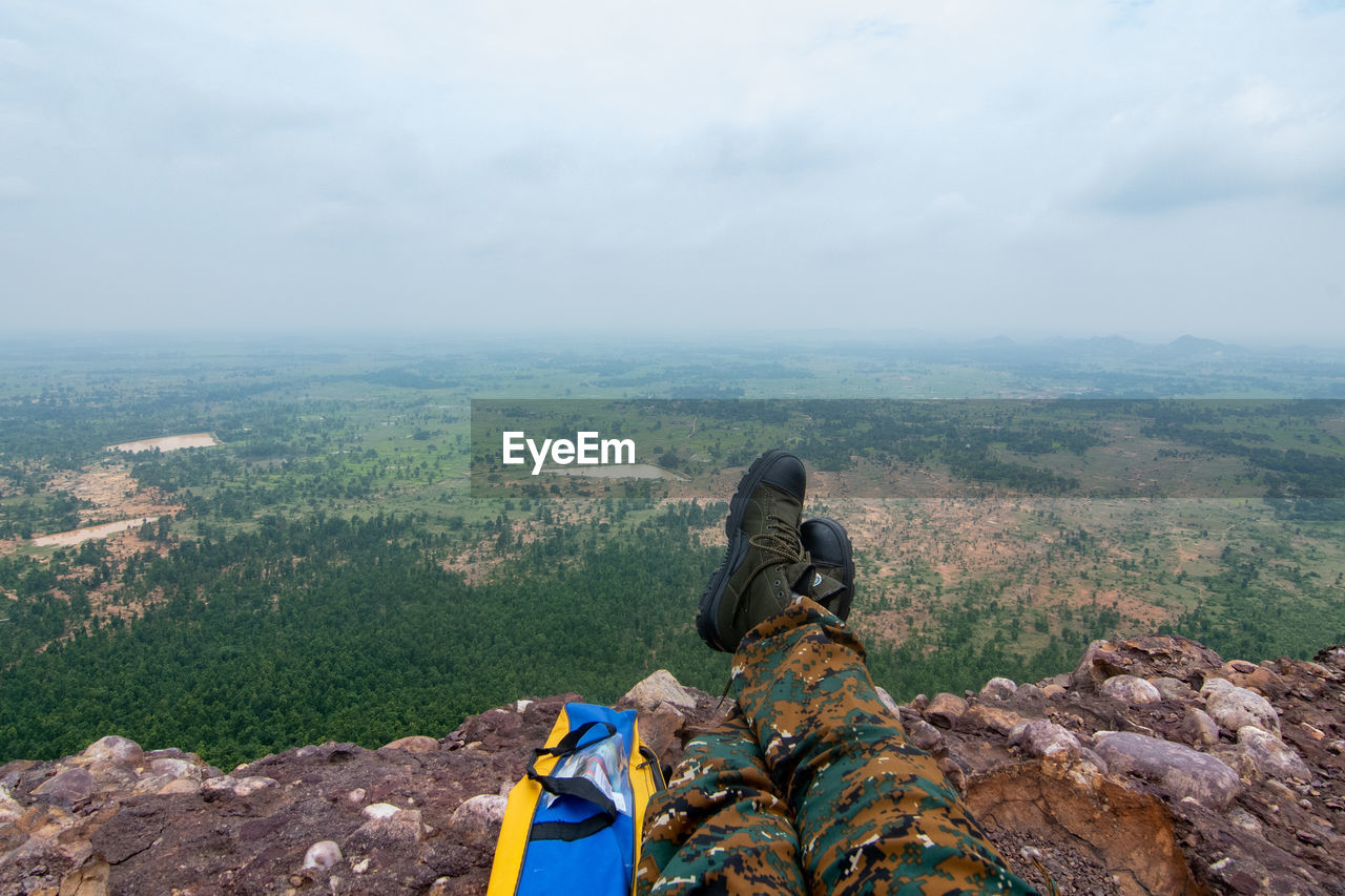 Rear view of man sitting on landscape against sky