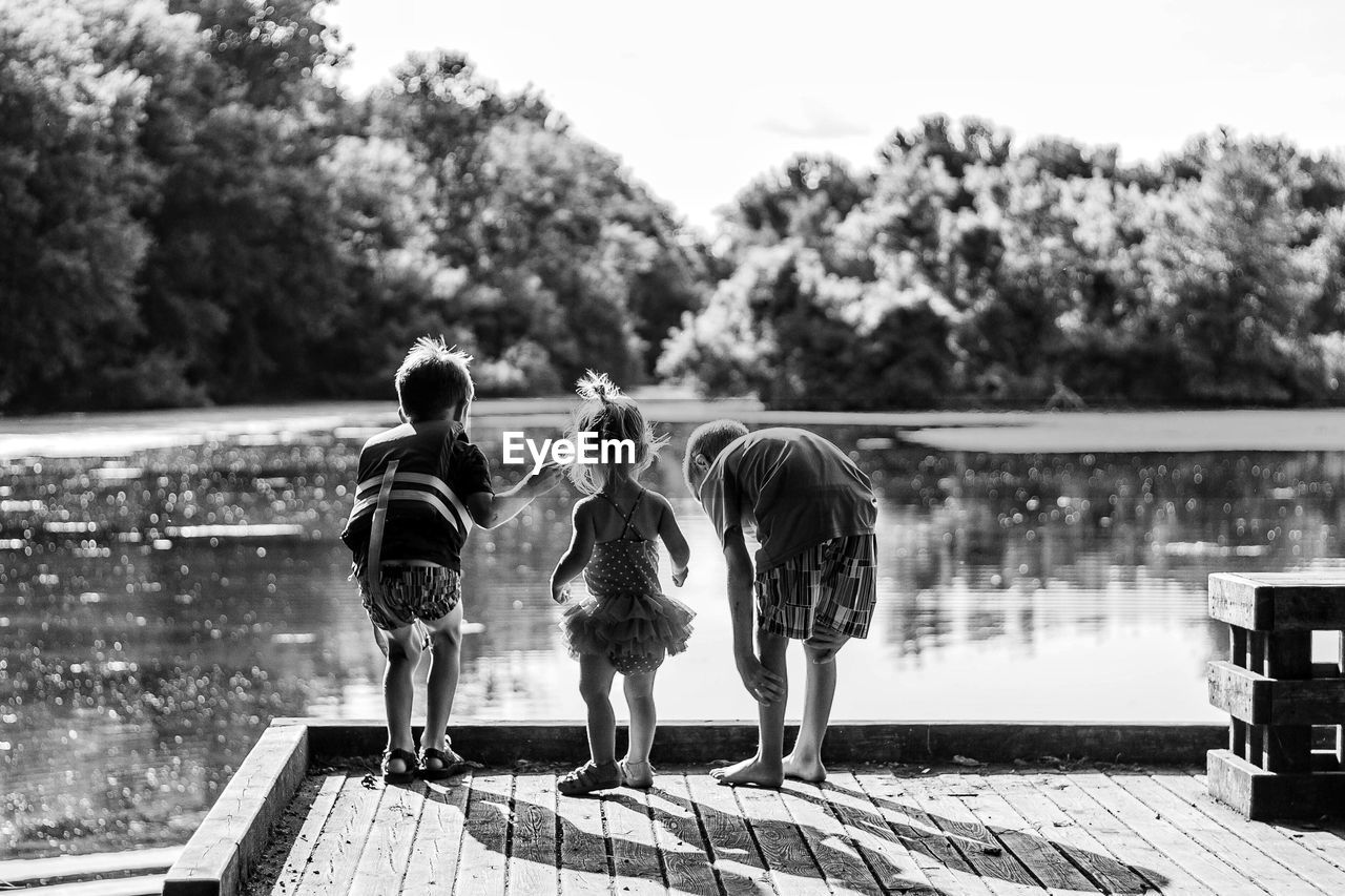 Rear view of children standing by lake
