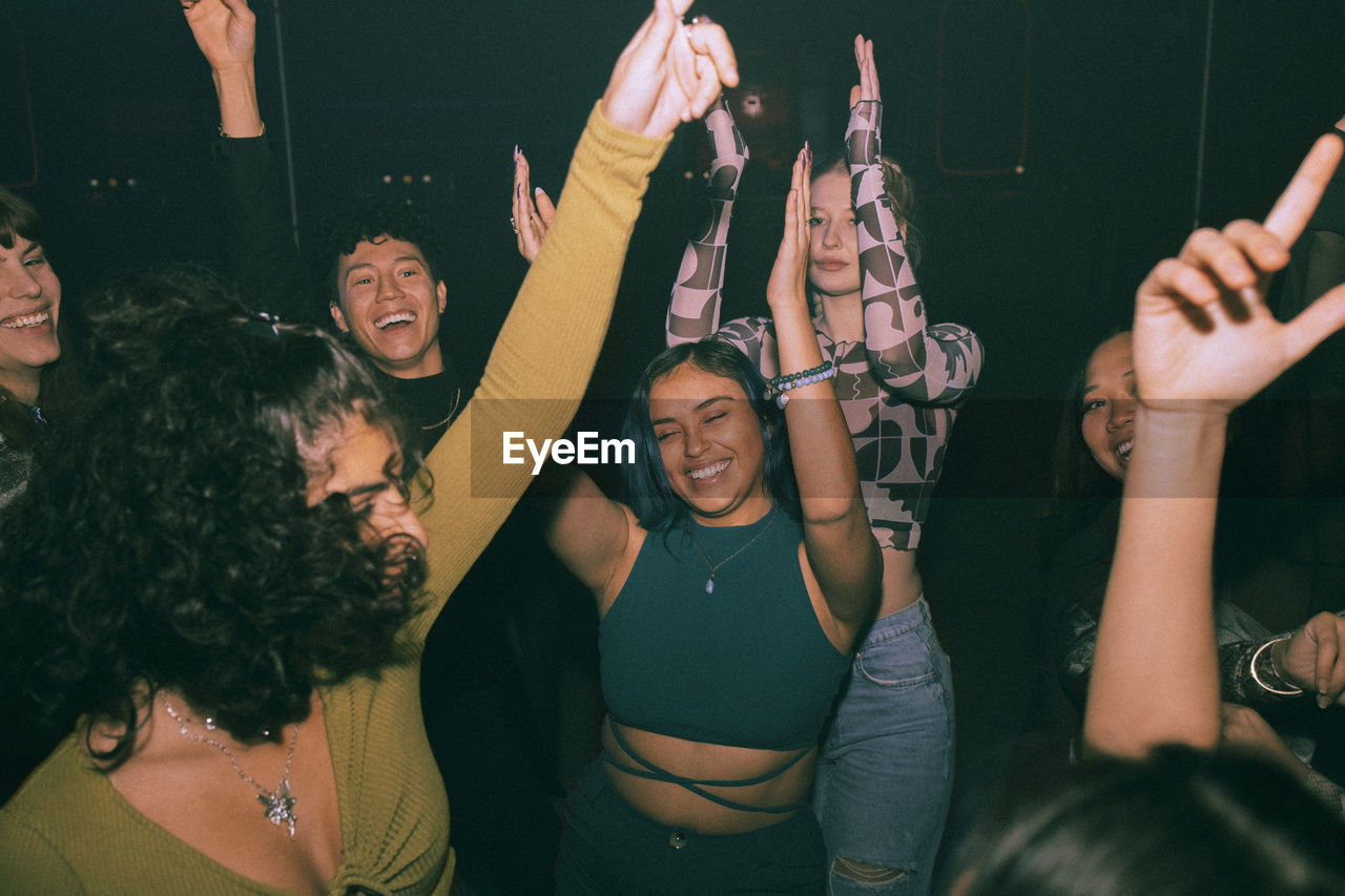 Cheerful young friends dancing and enjoying together at nightclub