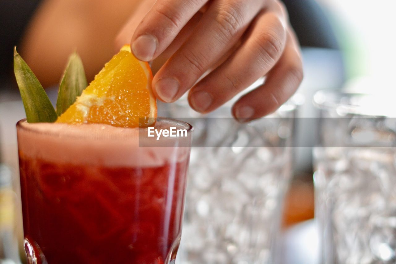 Cropped hand having drink on table