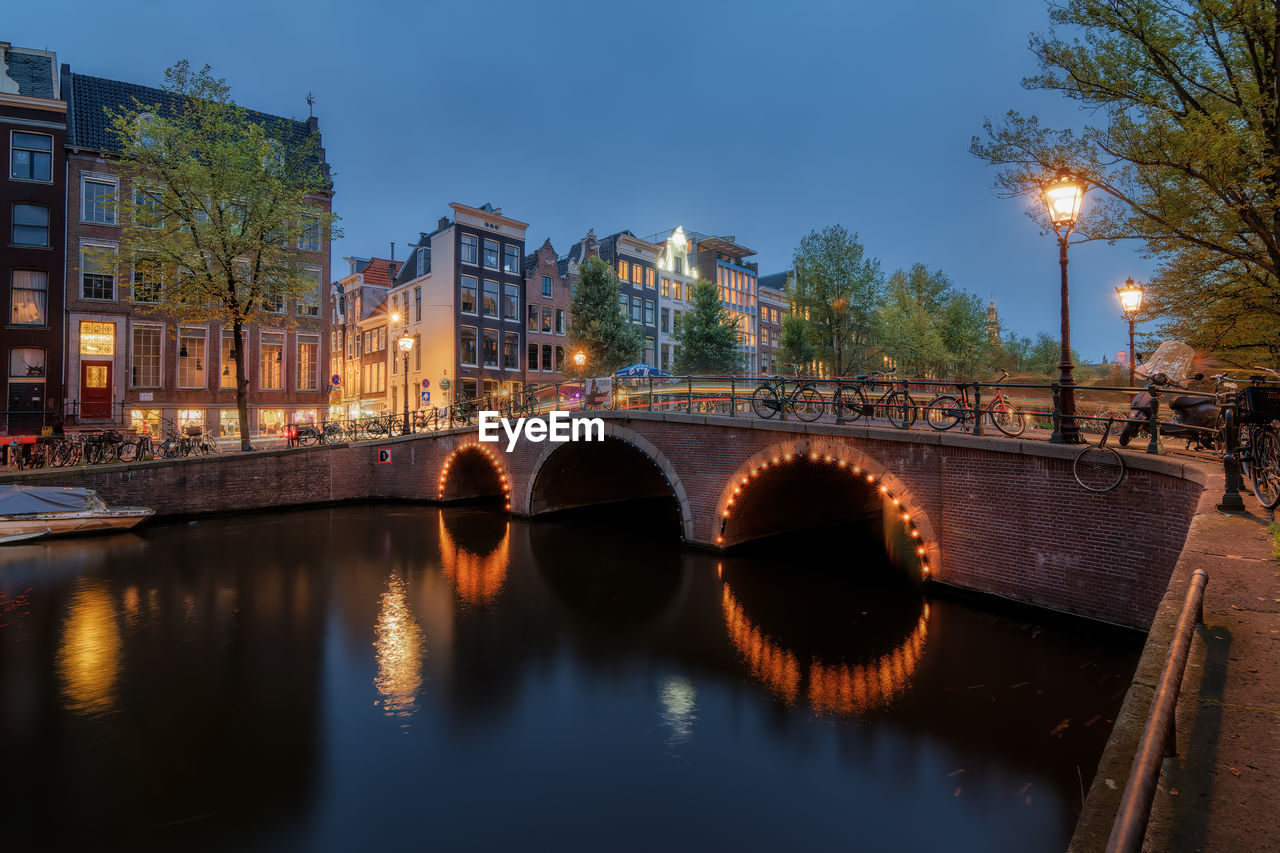 Illuminated bridge over the keizersgracht canal in amsterdam at dusk