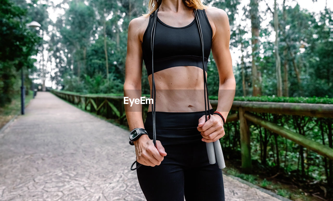 Unrecognizable athlete woman posing with skipping rope in a park