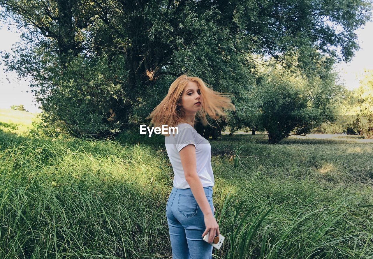 Portrait of beautiful woman standing on field in park