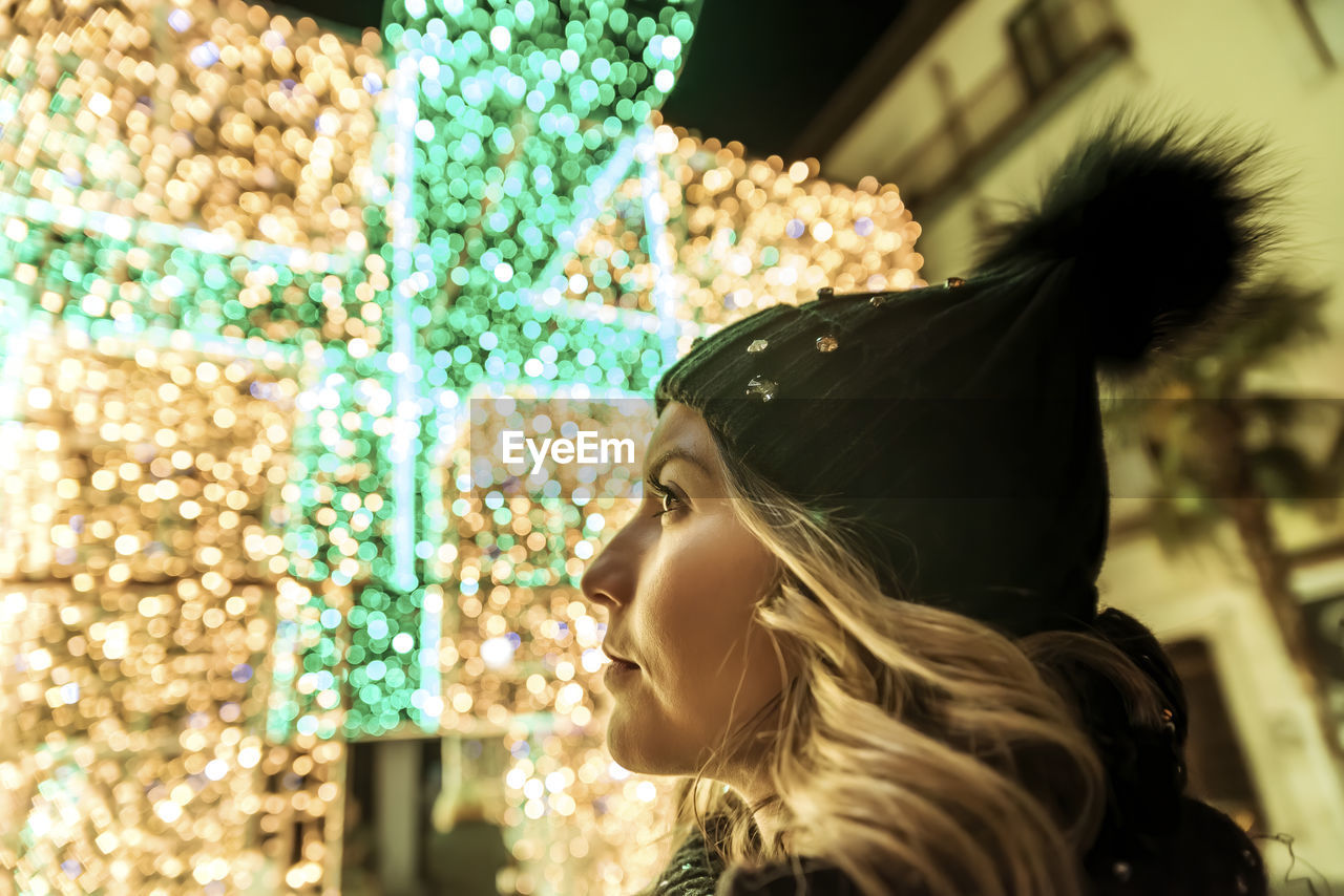 A young girl in a hat looking through christmas lights