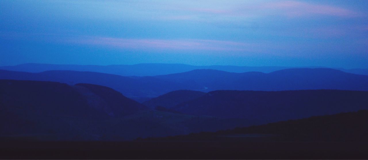 Scenic view of silhouette mountains against blue sky at night