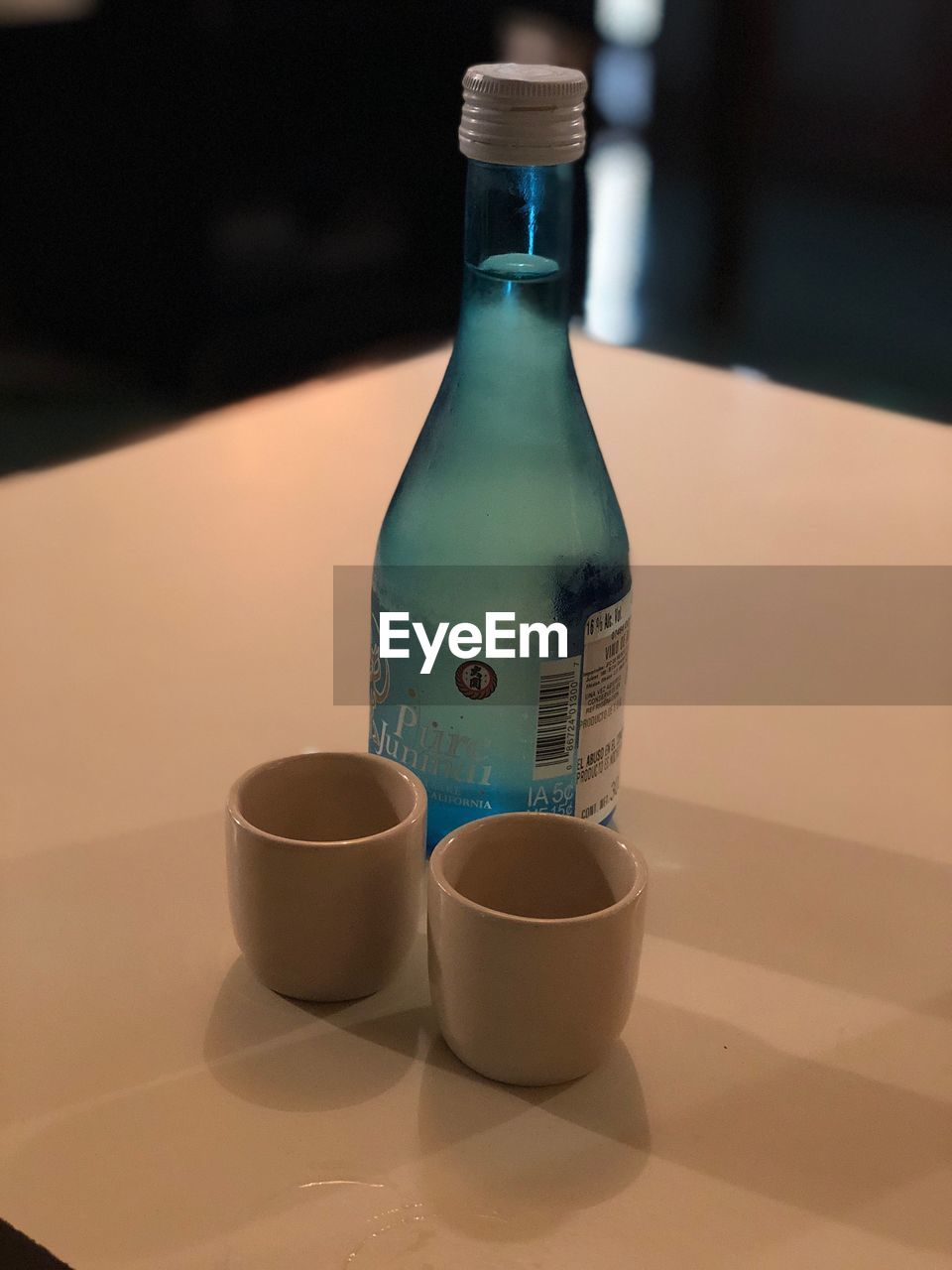 CLOSE-UP OF GLASS BOTTLE ON TABLE AT HOME