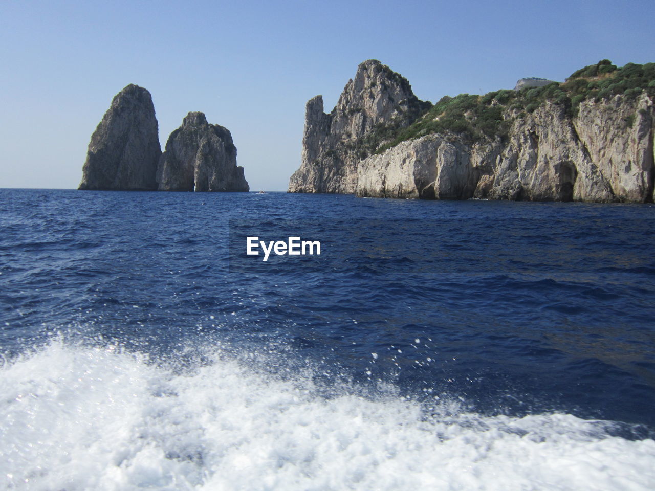 ROCKS IN SEA AGAINST CLEAR BLUE SKY