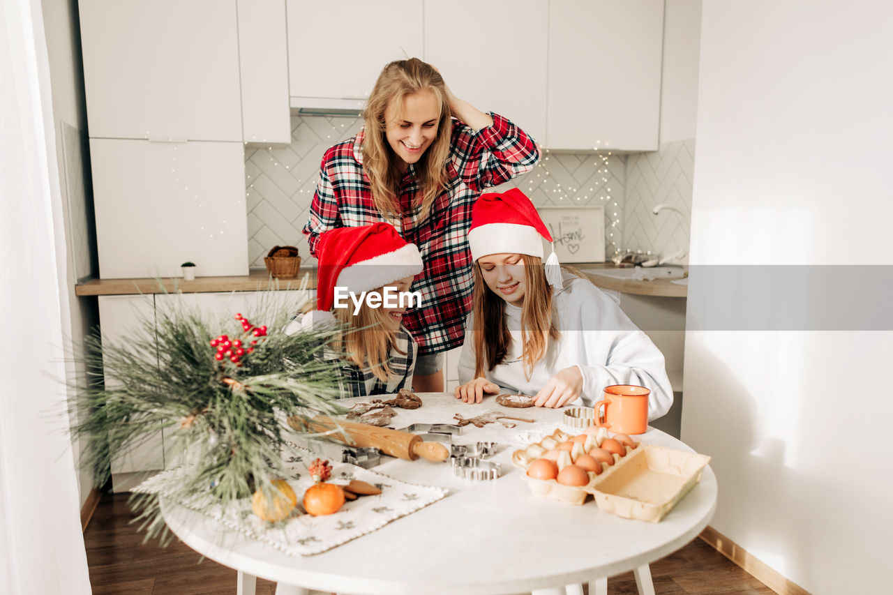 Mom and her daughters cook christmas cookies or gingerbread together, family cooking 