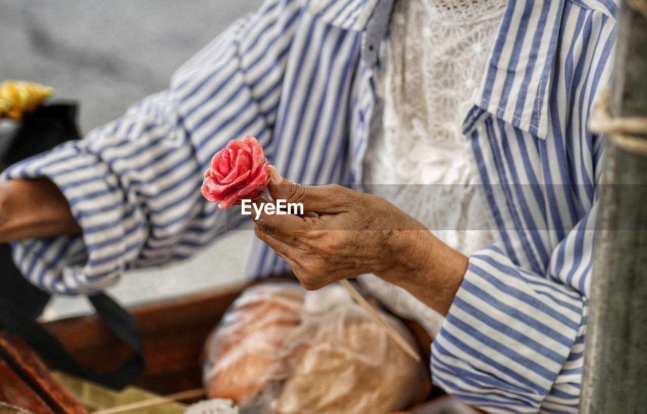 Midsection of man holding rose