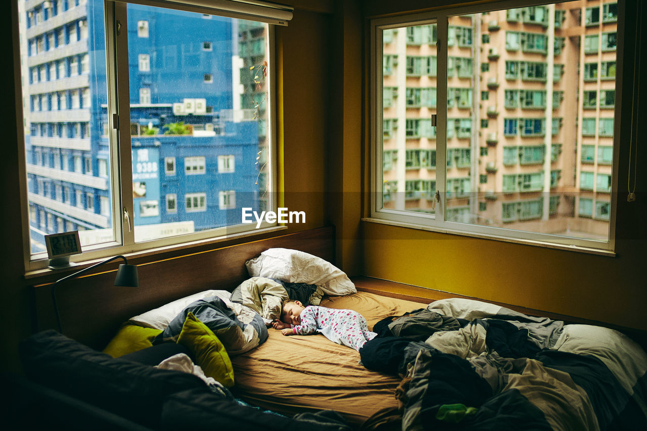 Cute baby sleeping on messy bed in house