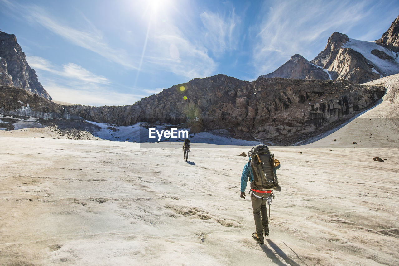 Mountaineers approach a headwall at the end of a glacier in mountains.