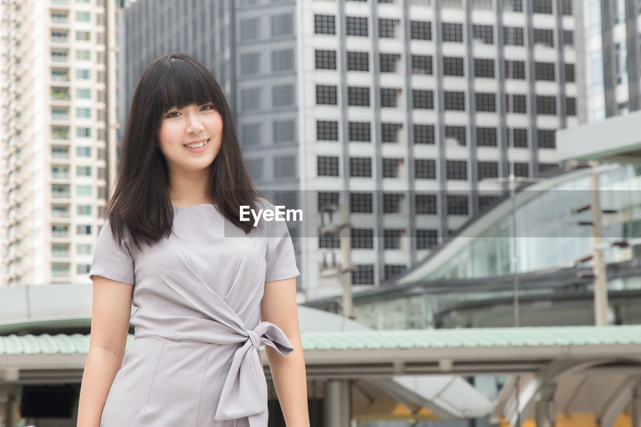 Young businesswoman standing against buildings in city