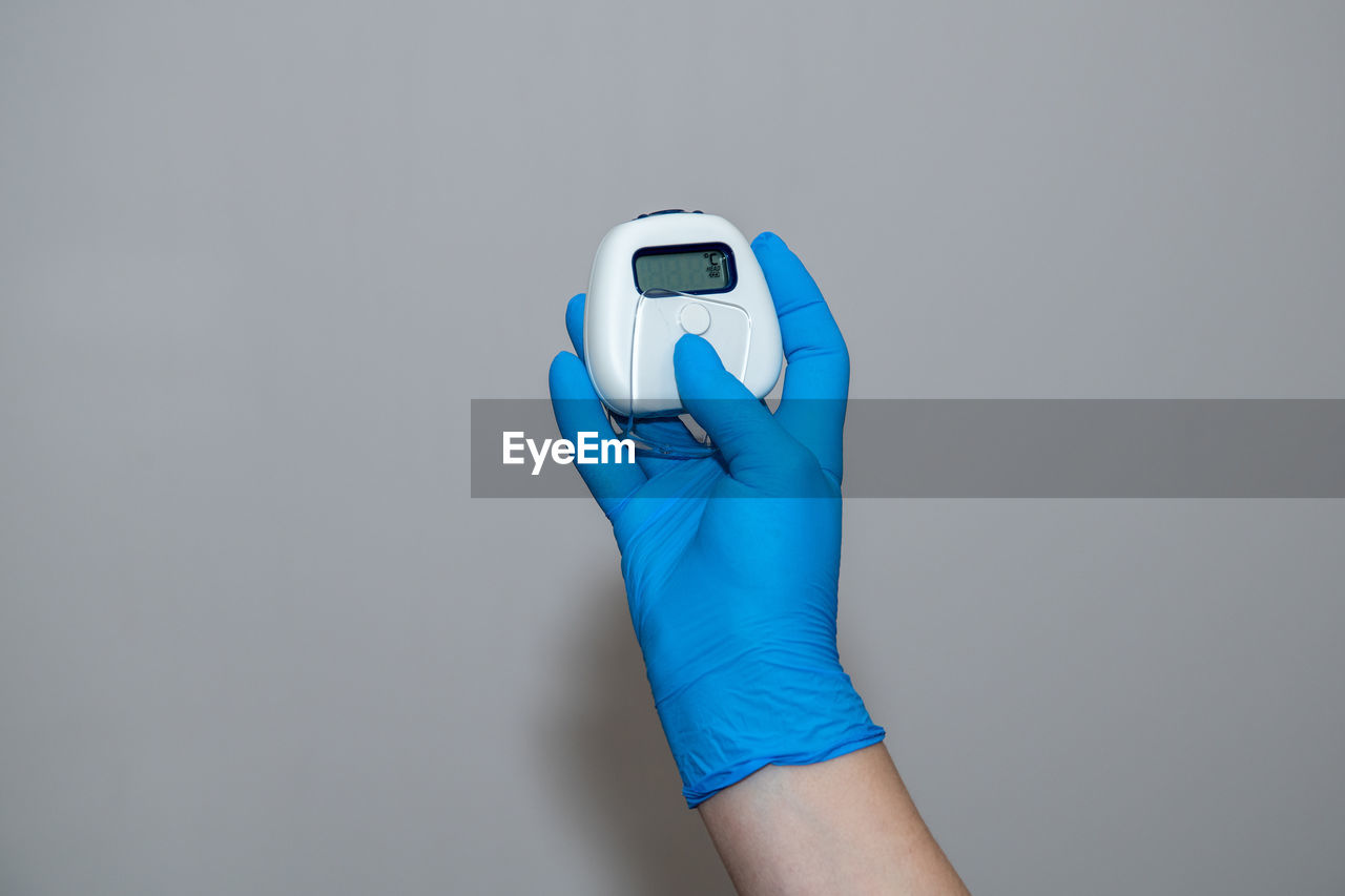 CLOSE-UP OF HAND HOLDING CAMERA OVER WHITE BACKGROUND