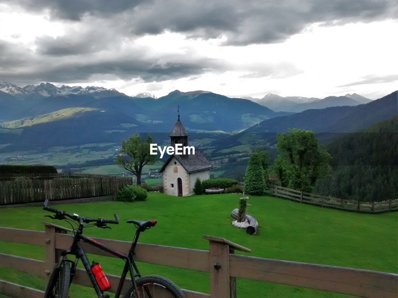 Bicycle and chapel on field against mountains