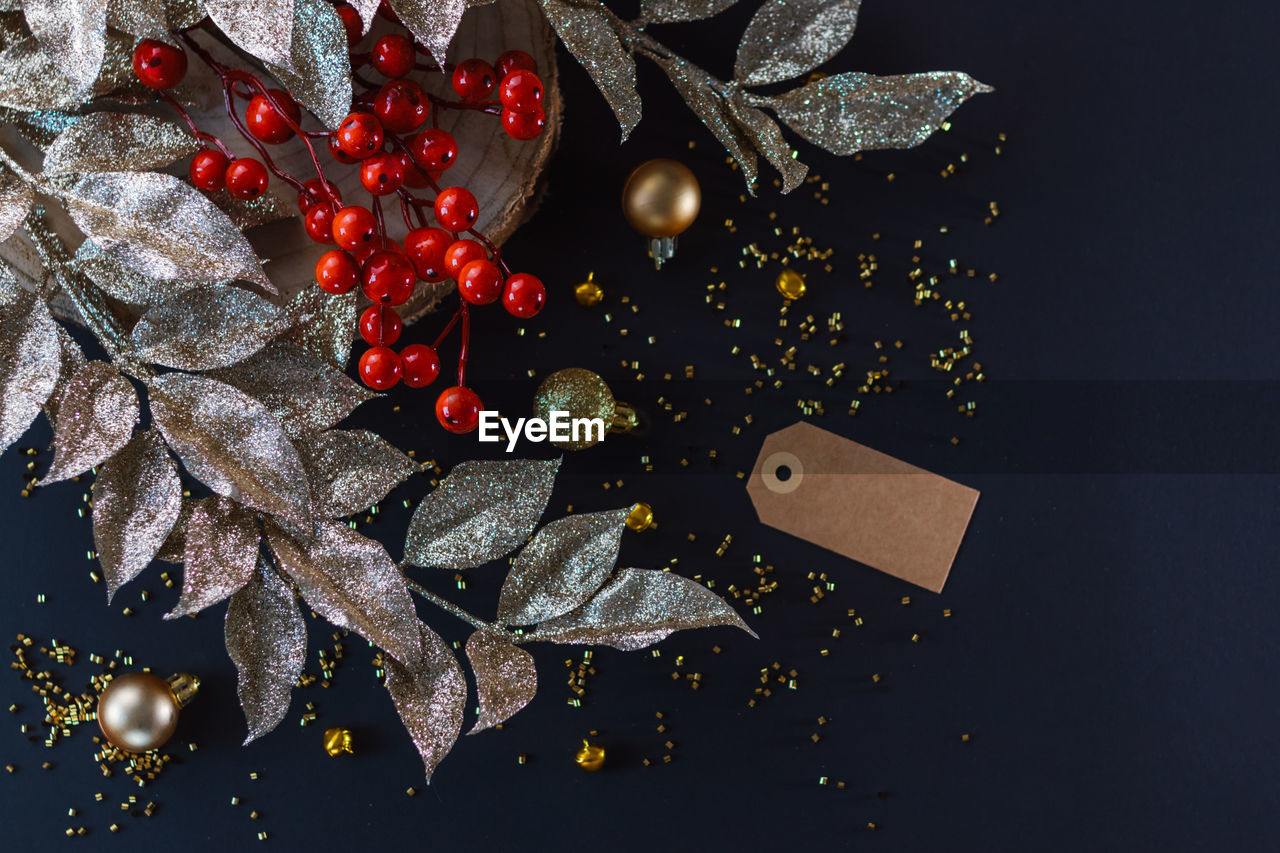 Golden christmas decoration on dark background. baubles, red berries and golden leaves.