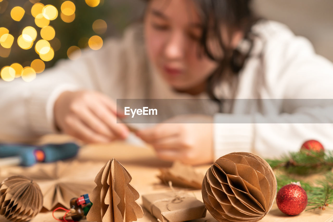Girl makes christmas tree decorations out of paper with her own hands. step-by-step instruction