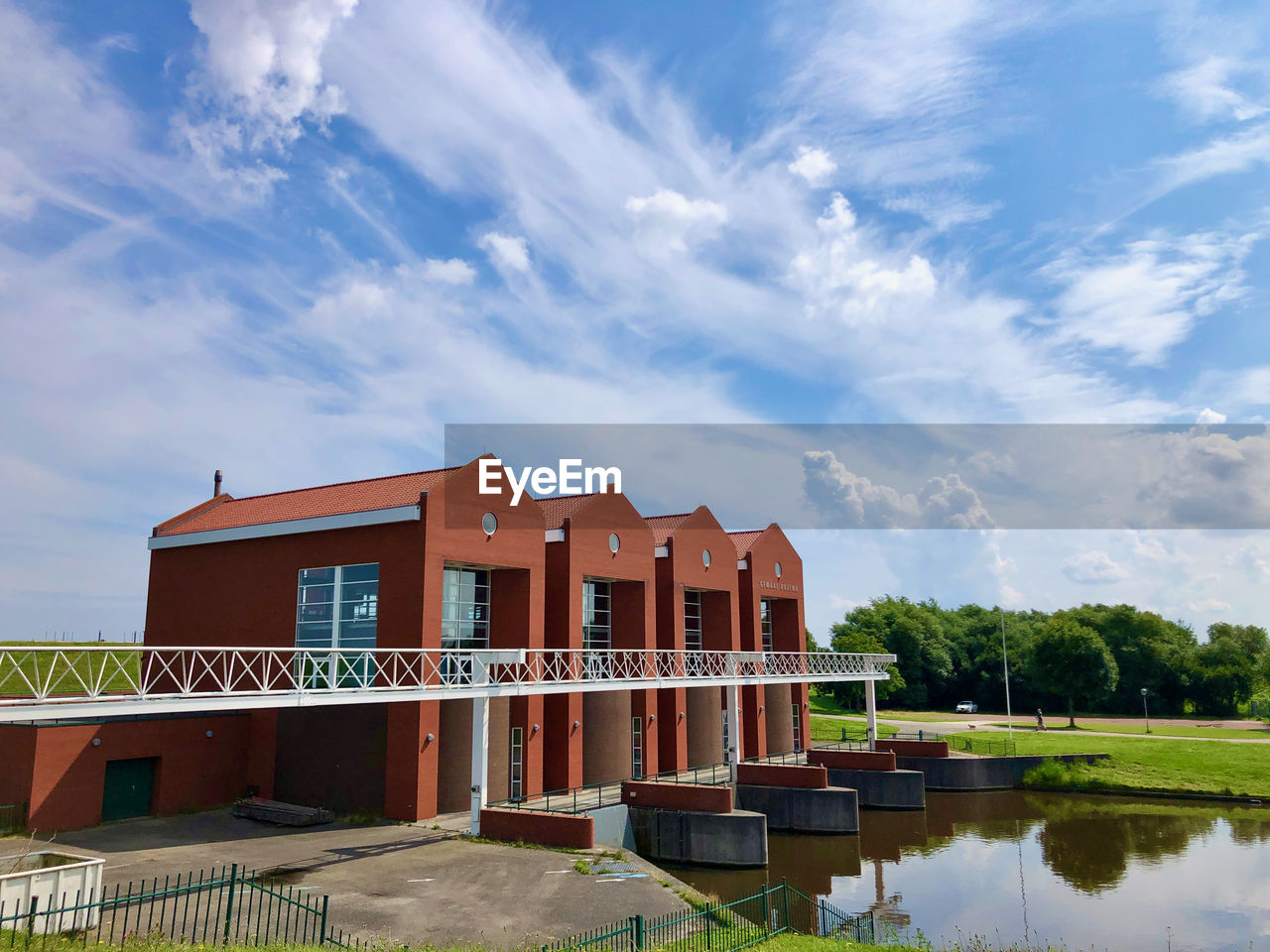 A well-designed red-colored pumping station under a sky full of white clouds
