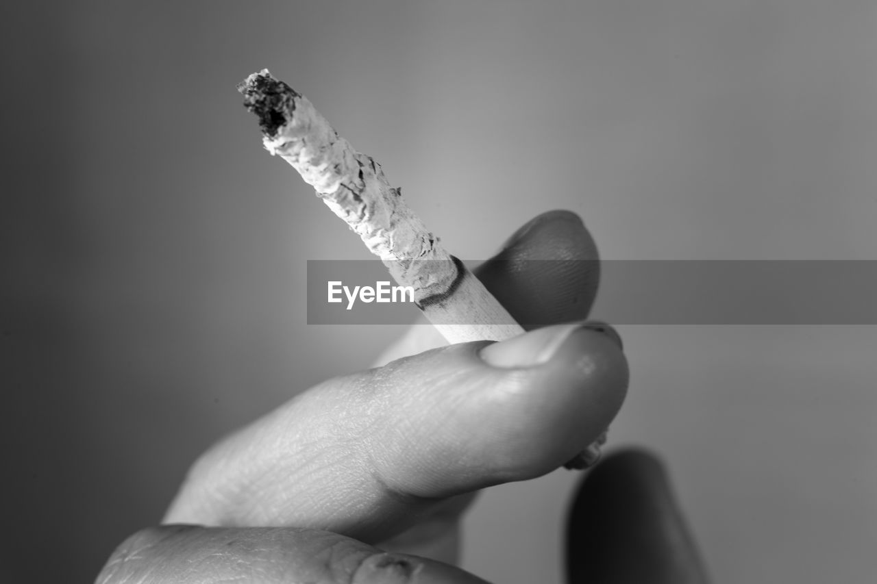 Cropped hand of person holding lit cigarette