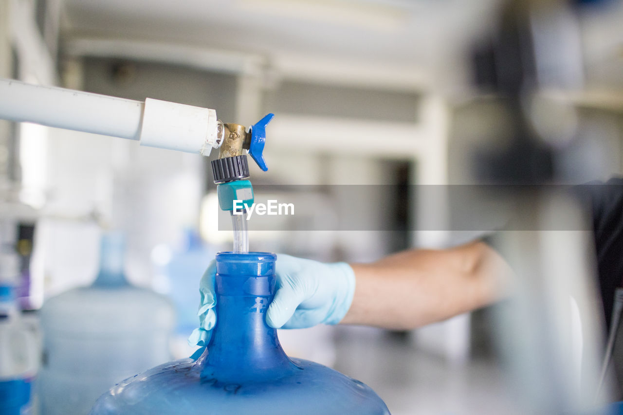 Worker holds top of water jug while filling it with drinking water.