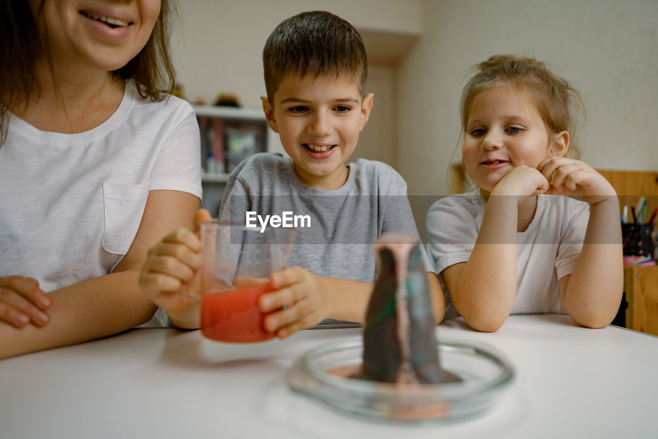 Mom and children at home are conducting an experiment with a volcanic eruption.