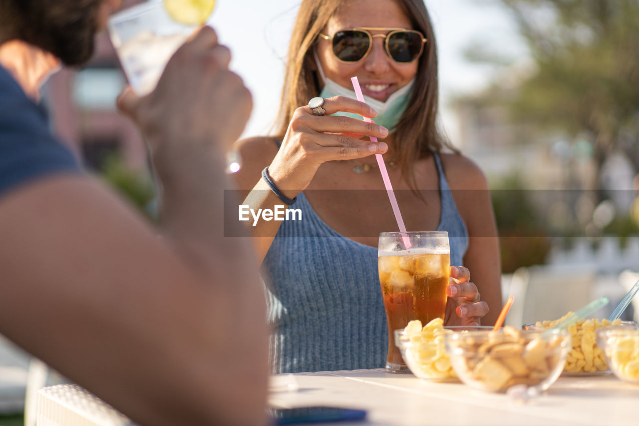 Young woman with sunglasses drinking cocktails. new normal friends reunion coronavirus lockdown.