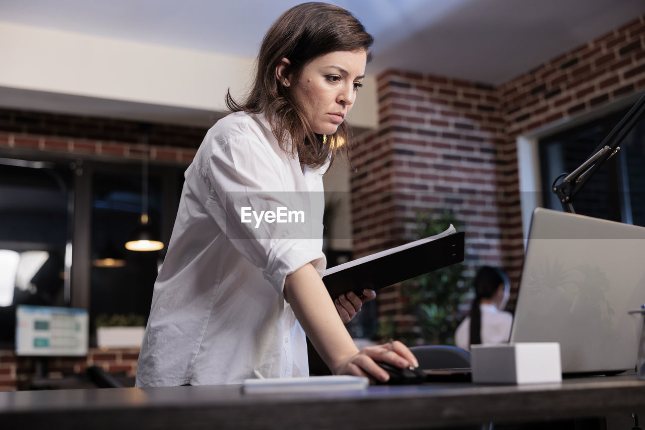 Side view of young woman using laptop while working in office