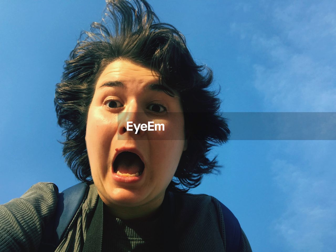 Close-up of woman screaming against blue sky