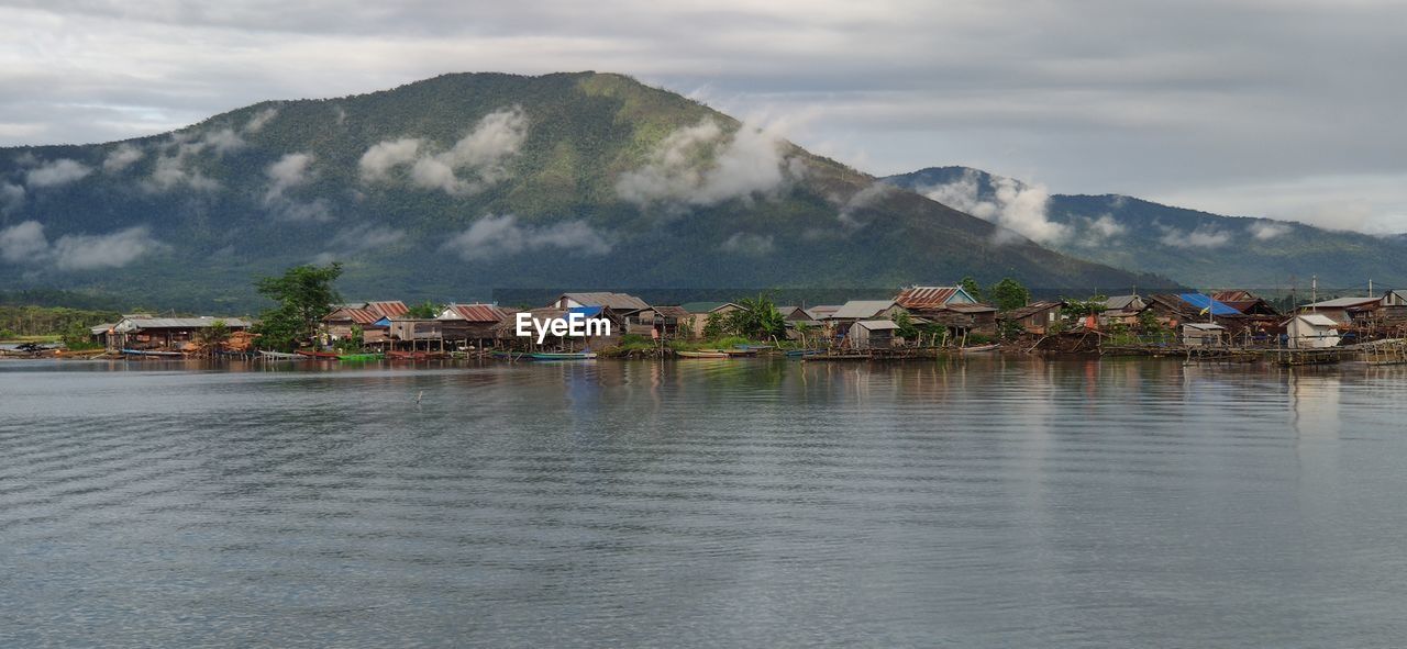 TOWN BY LAKE AND MOUNTAINS AGAINST SKY