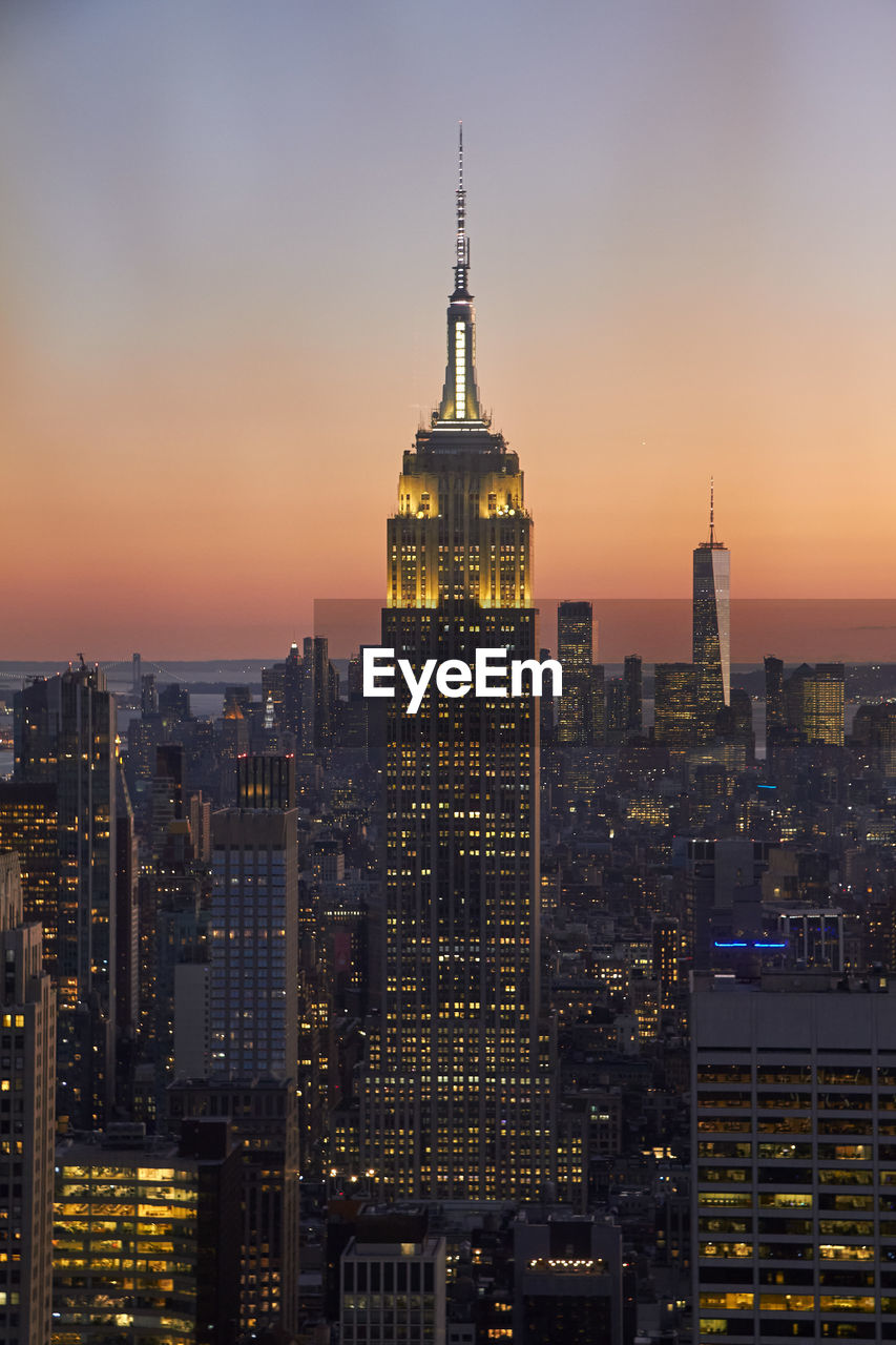 Illuminated empire state building in new york at sunset