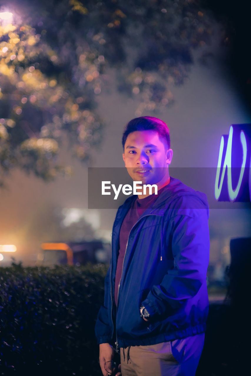 Portrait of young man standing outdoors at night