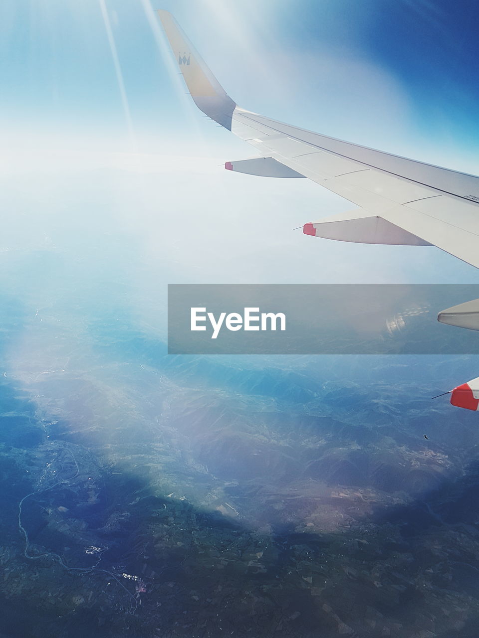 CROPPED IMAGE OF AIRPLANE WING OVER LANDSCAPE